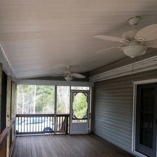 Screened porch with dark wood floor, ceiling fans, and a door leading outside.