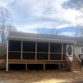 Screened porch with stairs and door; brown deck, gray siding, white trim, blue sky.