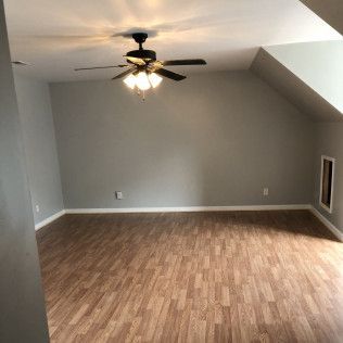 Empty room with gray walls, wood-look floor, and ceiling fan.