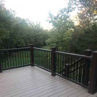 Deck with brown railings and composite decking, overlooking green trees.