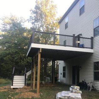 Elevated deck attached to a house with stairs leading to the yard. Brown and white construction.