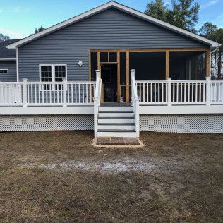 A house with a blue exterior and a white deck with stairs leading to a screened-in porch.