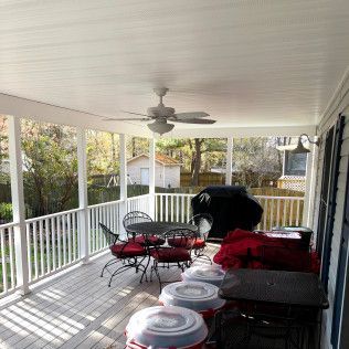 Covered porch with white railings, ceiling fan, and patio furniture.