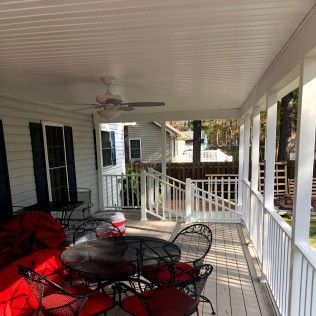 Covered porch with white trim, ceiling fan, table, chairs, and view of other houses.