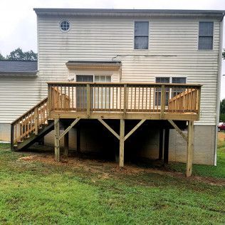 Wooden deck attached to a two-story house, with steps leading down to a grassy yard.