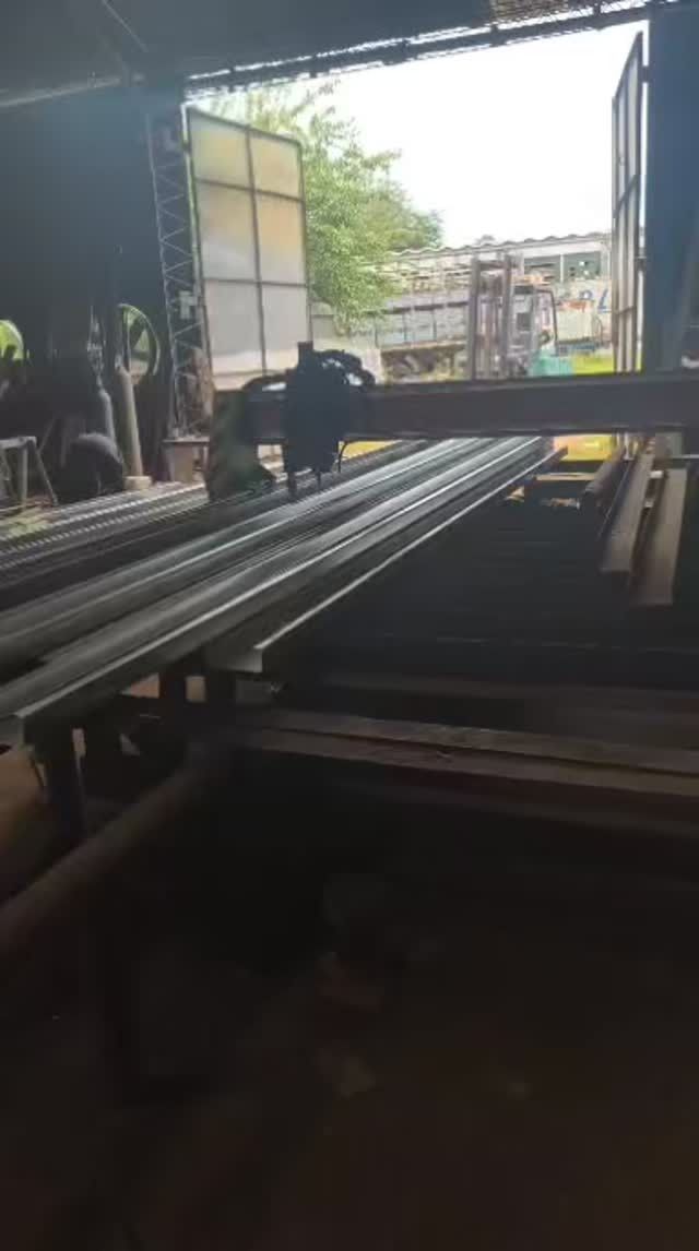 Tubos metálicos largos sobre un soporte en un taller industrial abierto.