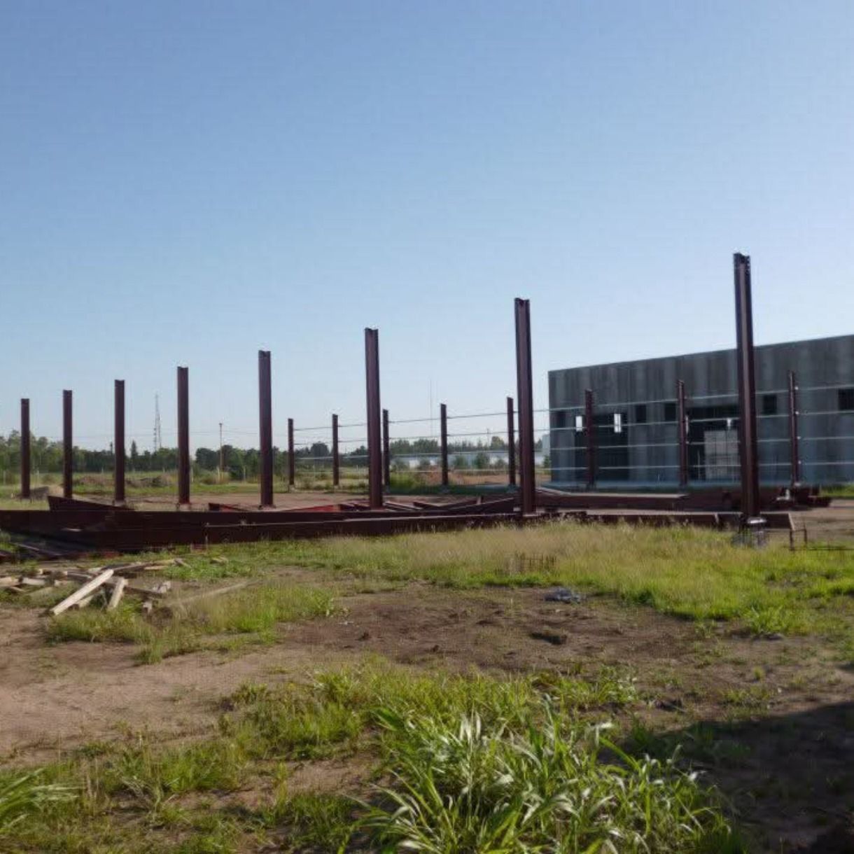 Obra en construcción al aire libre con postes de acero, una estructura metálica parcialmente construida