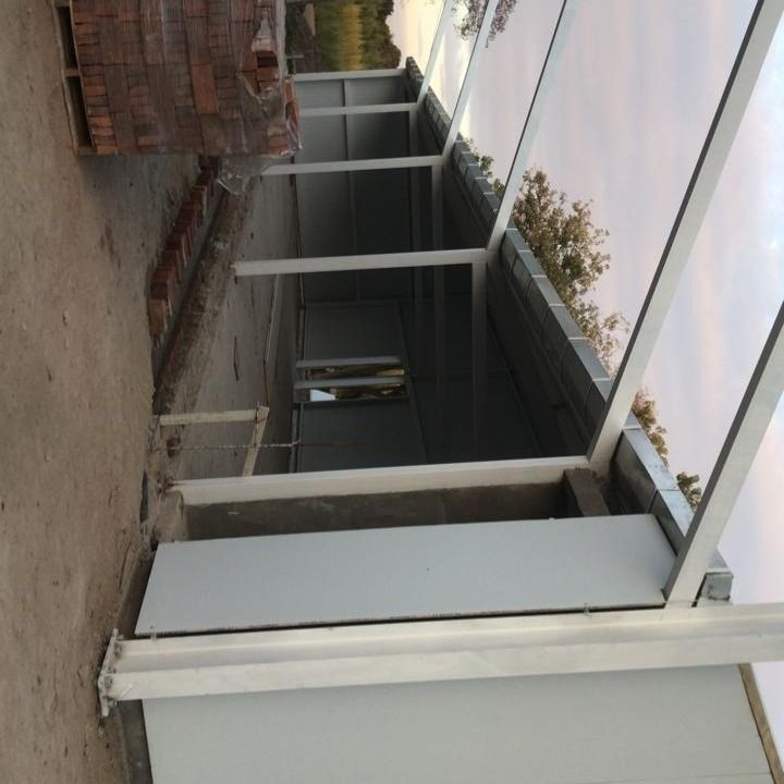 Pasarela cubierta junto a un edificio con columnas blancas y estructura metálica, vista desde un ángulo inclinado.