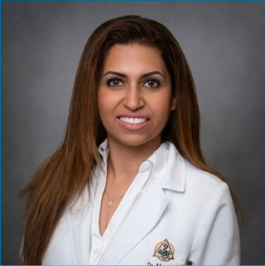 Portrait of a woman in a white medical coat against a gray studio backdrop