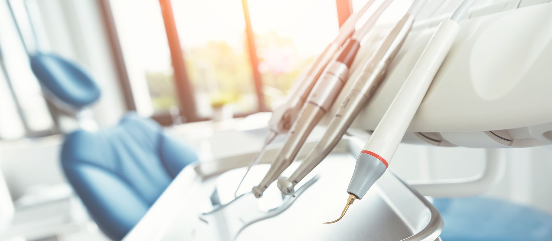 Dental tools beside a bright blue dentist chair in a modern clinic
