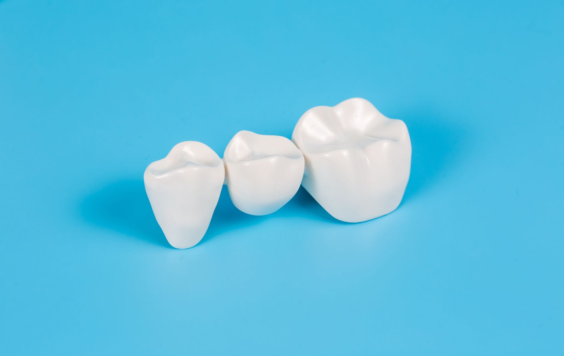 Three white dental crowns on a blue background