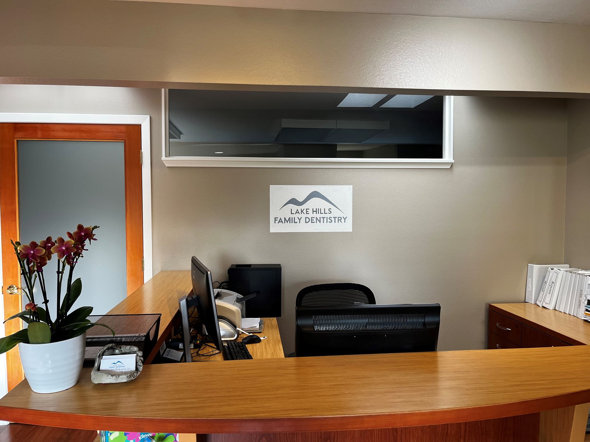 The front desk of a dental office with a sign on the wall that says Lake Hills Family Dentistry.