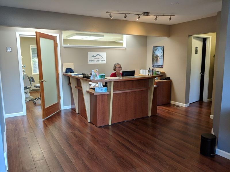 A woman is sitting at a desk in a reception area of Lake Hills Family Dentistry