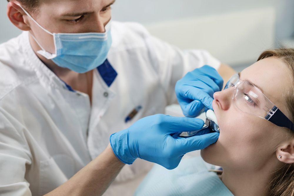 A woman is getting her teeth examined by a dentist
