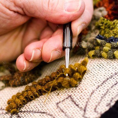 Hand using a crochet hook to work yellow yarn on patterned fabric