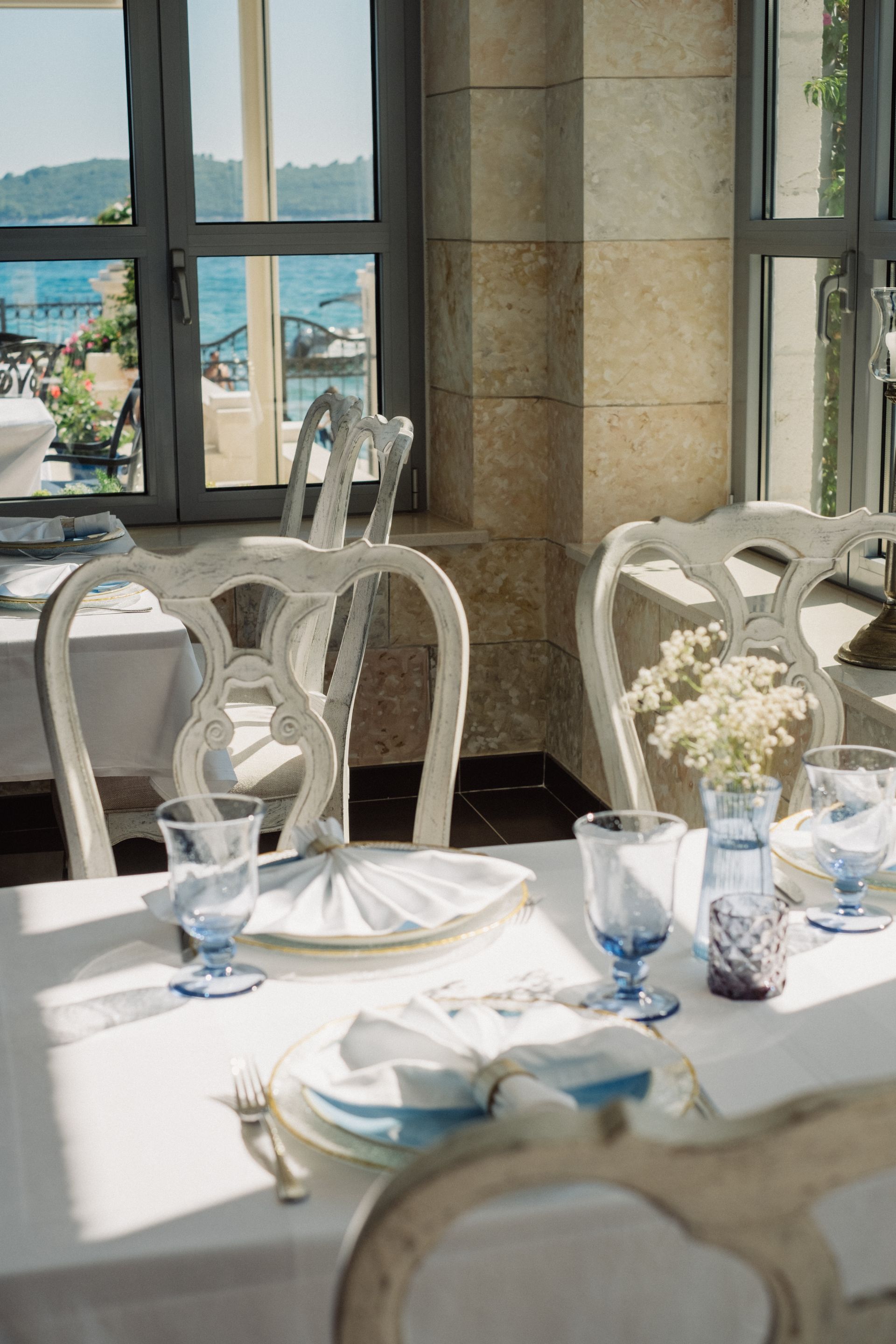 A table with plates and glasses on it in front of a window, Kapetanov Dvor