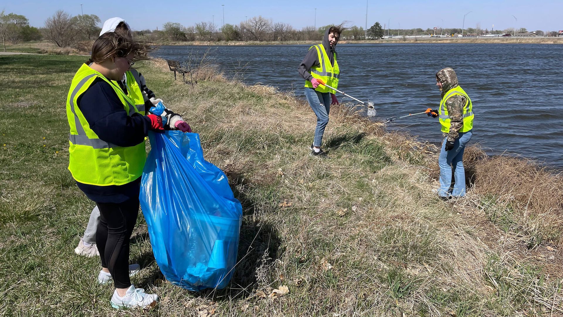 A group of people are cleaning the shore of a lake.