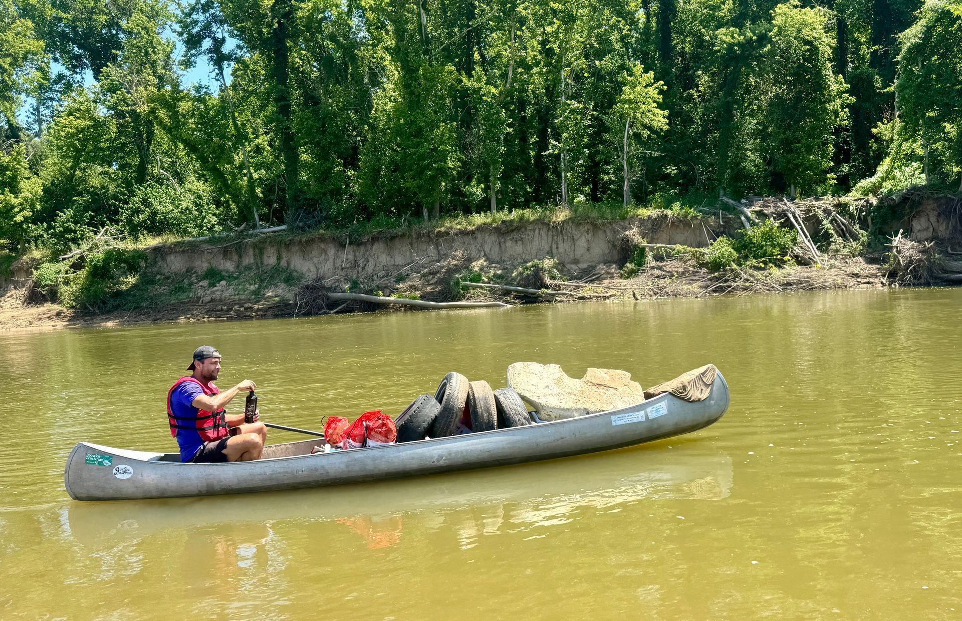A man is sitting in a canoe on a river.