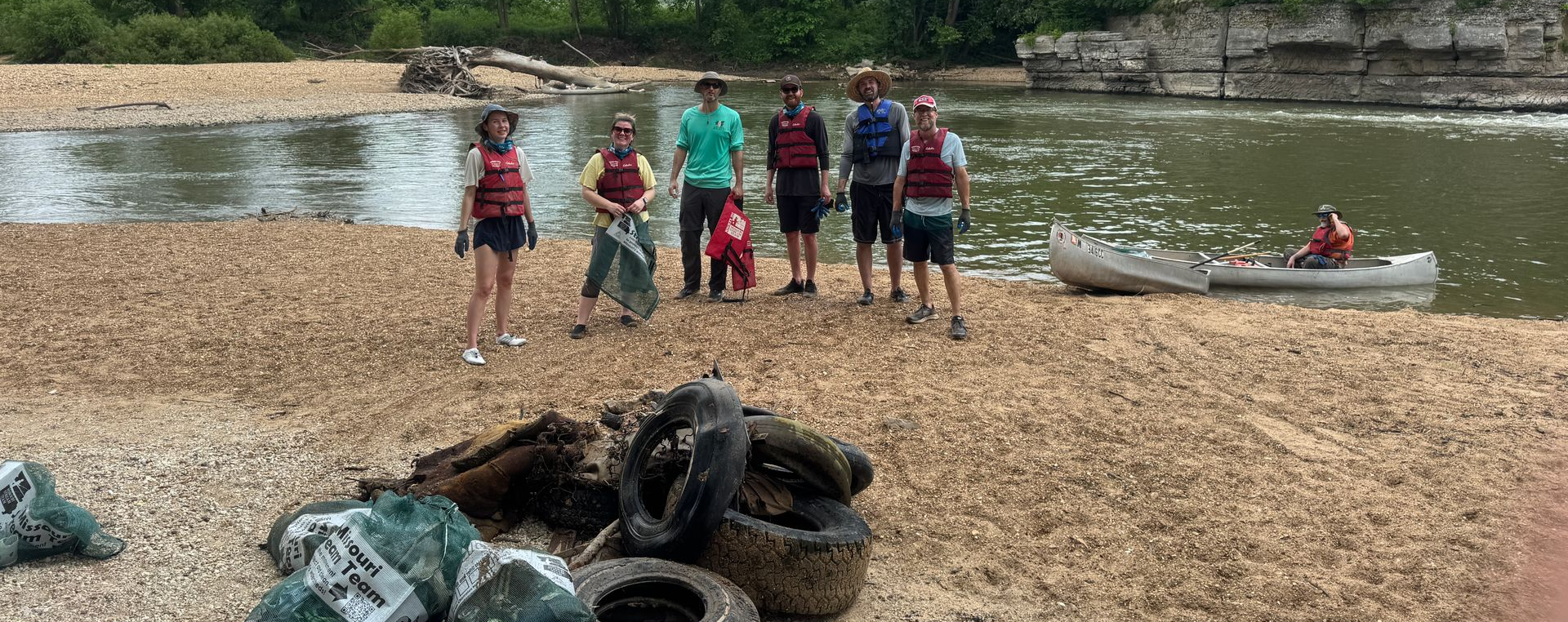 A group of people are posing after a stream clean up.