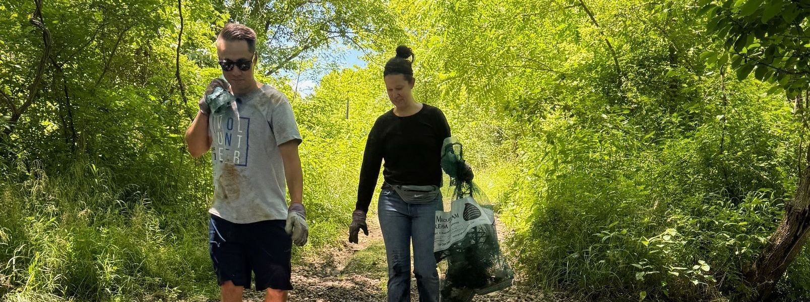 A man and a woman are walking down a path in the woods.