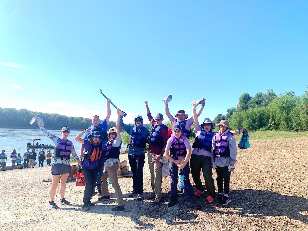 A group of people standing on a beach with their arms in the air