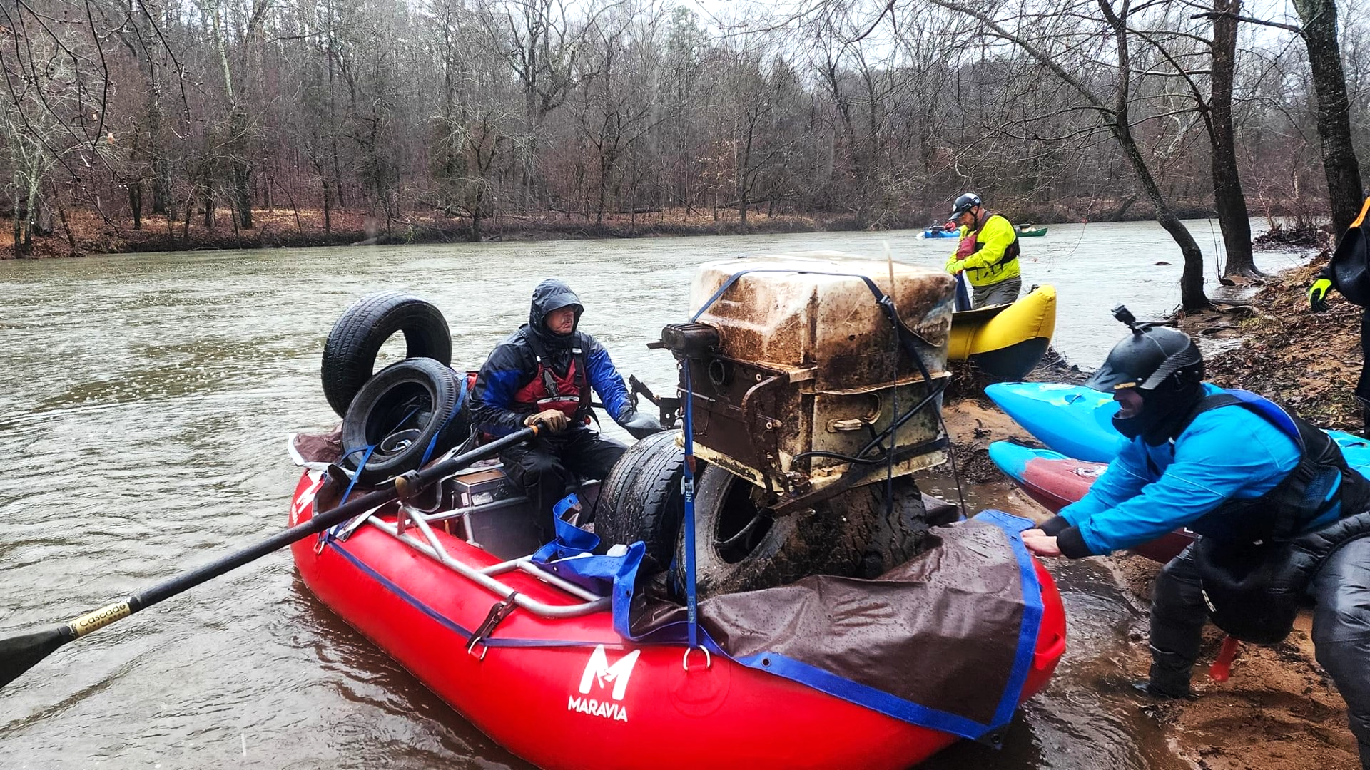 A group of people are rowing a red raft down a river.
