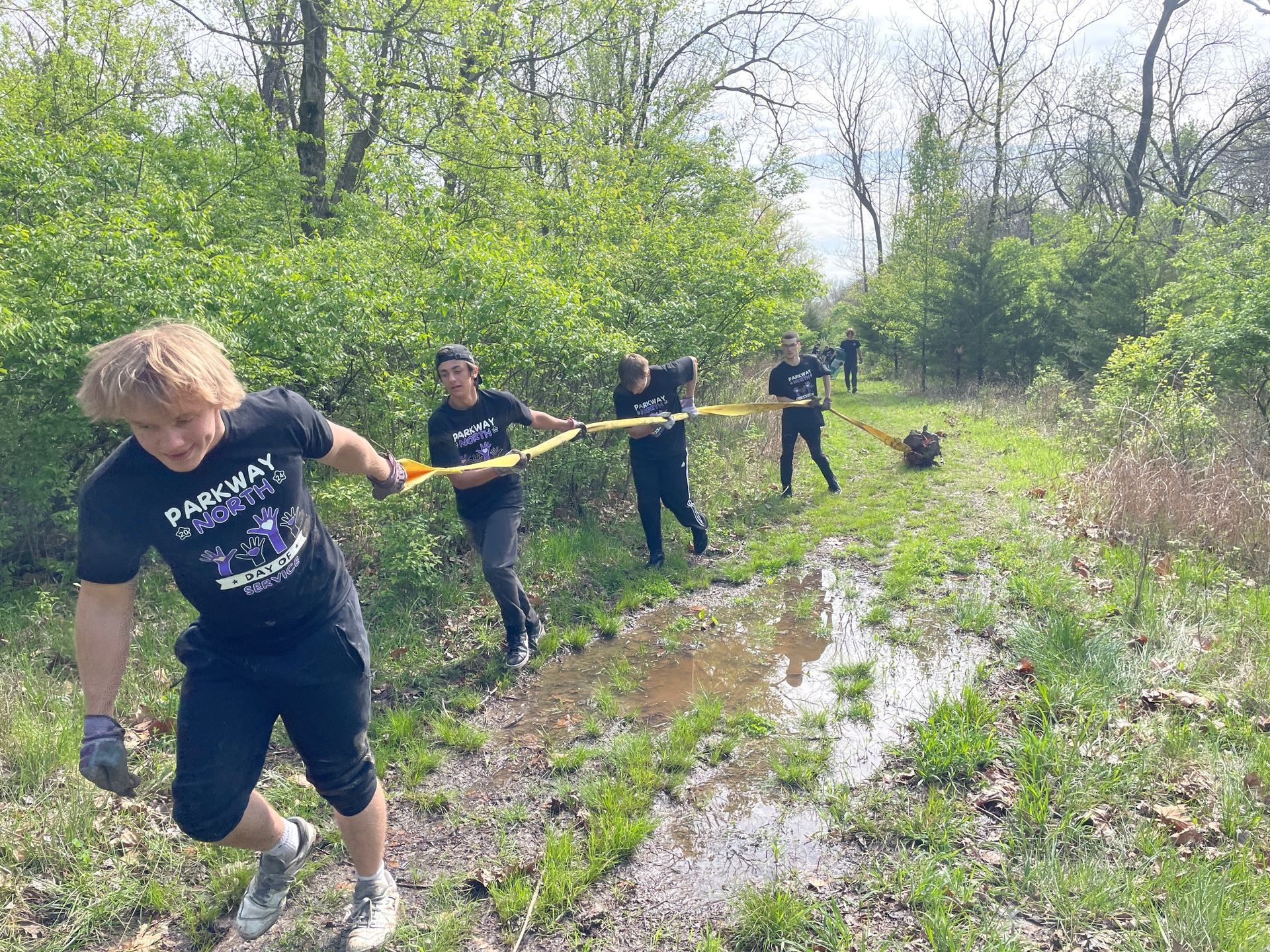 A group of people are running through a muddy field.