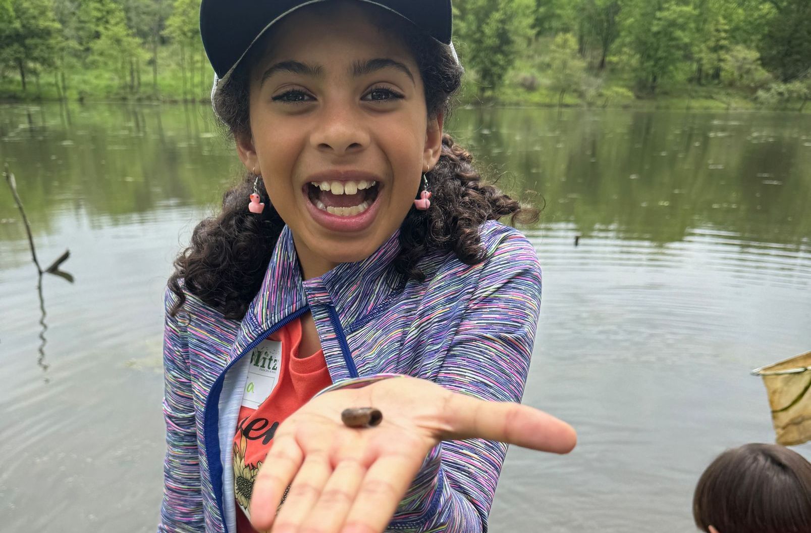 A young girl is holding a small bug in her hand.
