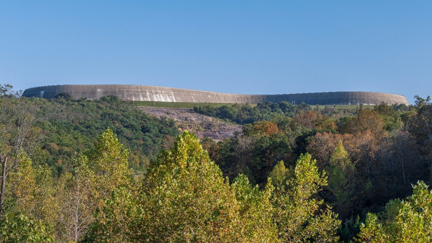 Wide stone wall atop a forested ridge under a clear blue sky