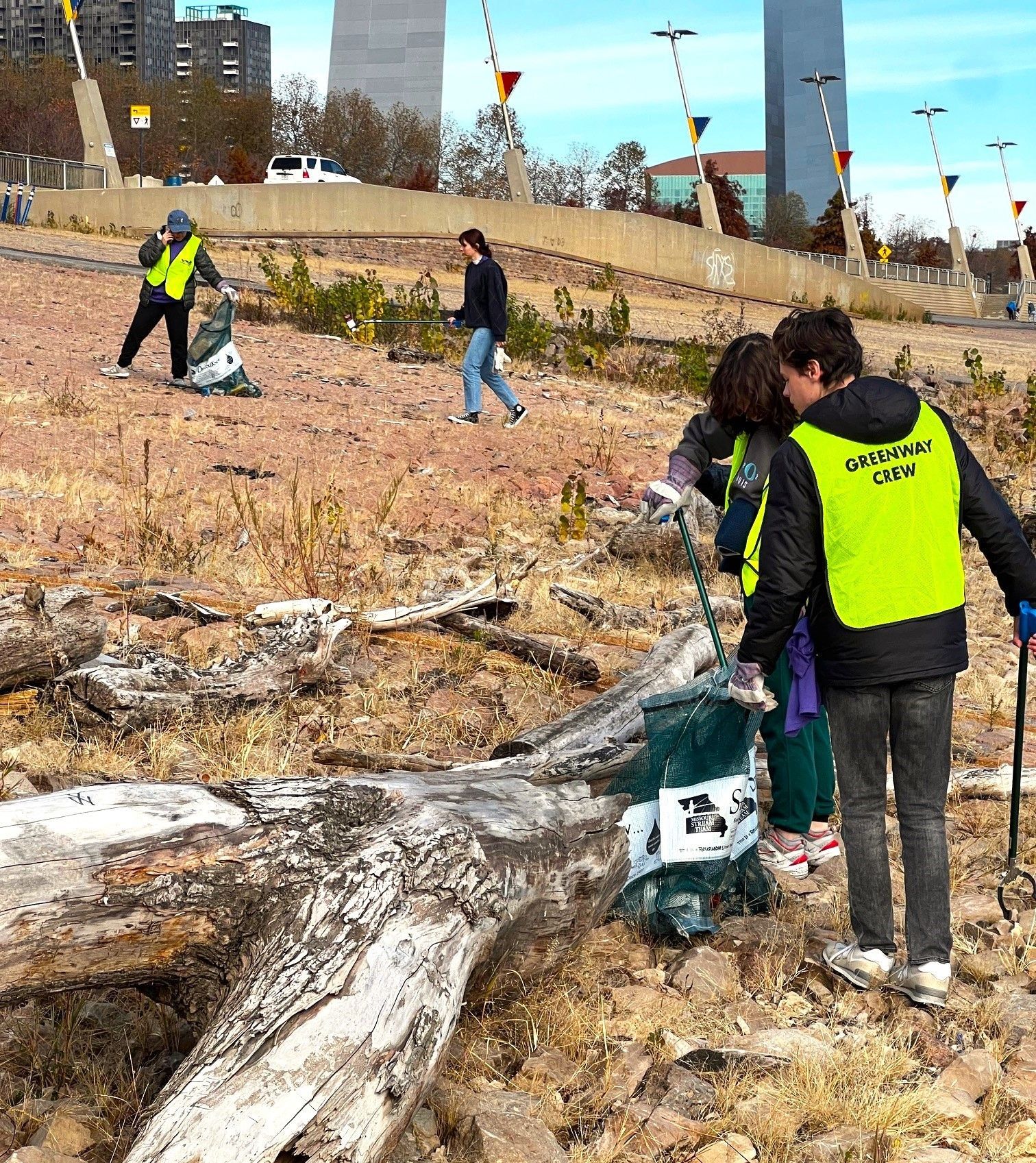 A group of people wearing yellow vests are standing in a field.