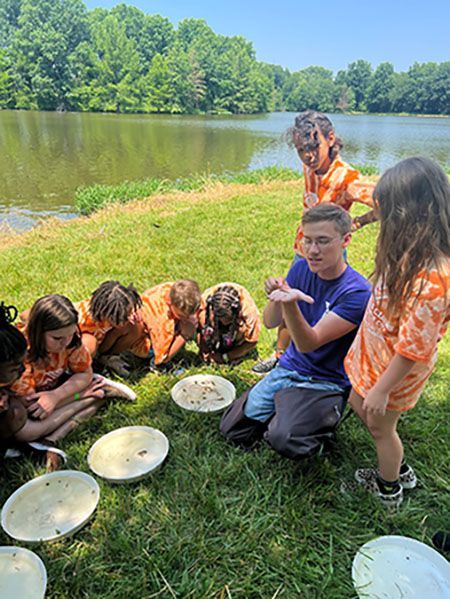 A group of children are sitting on the grass with plates of food.
