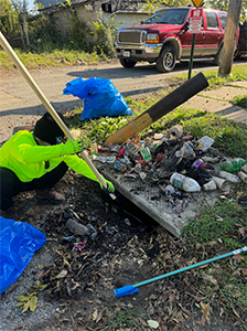 A person is cleaning a trash can with a broom.