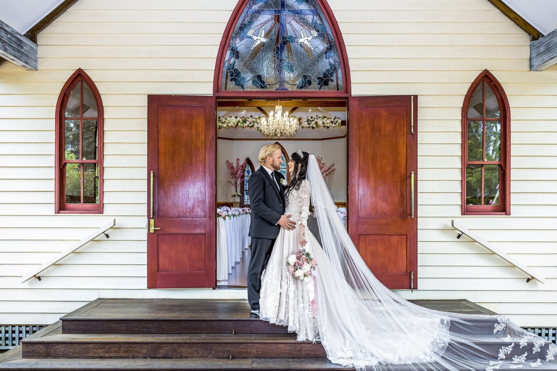 Wedding Videography - a bride and groom are posing for a picture in front of a church .