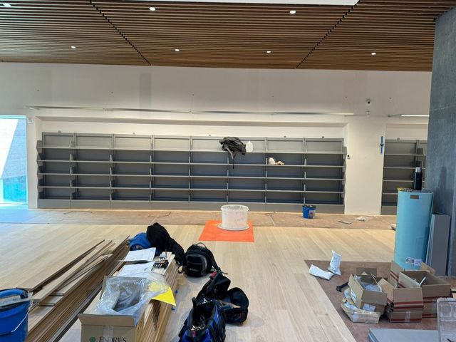 Empty retail store interior with shelves, wood ceiling, and renovation materials on the floor