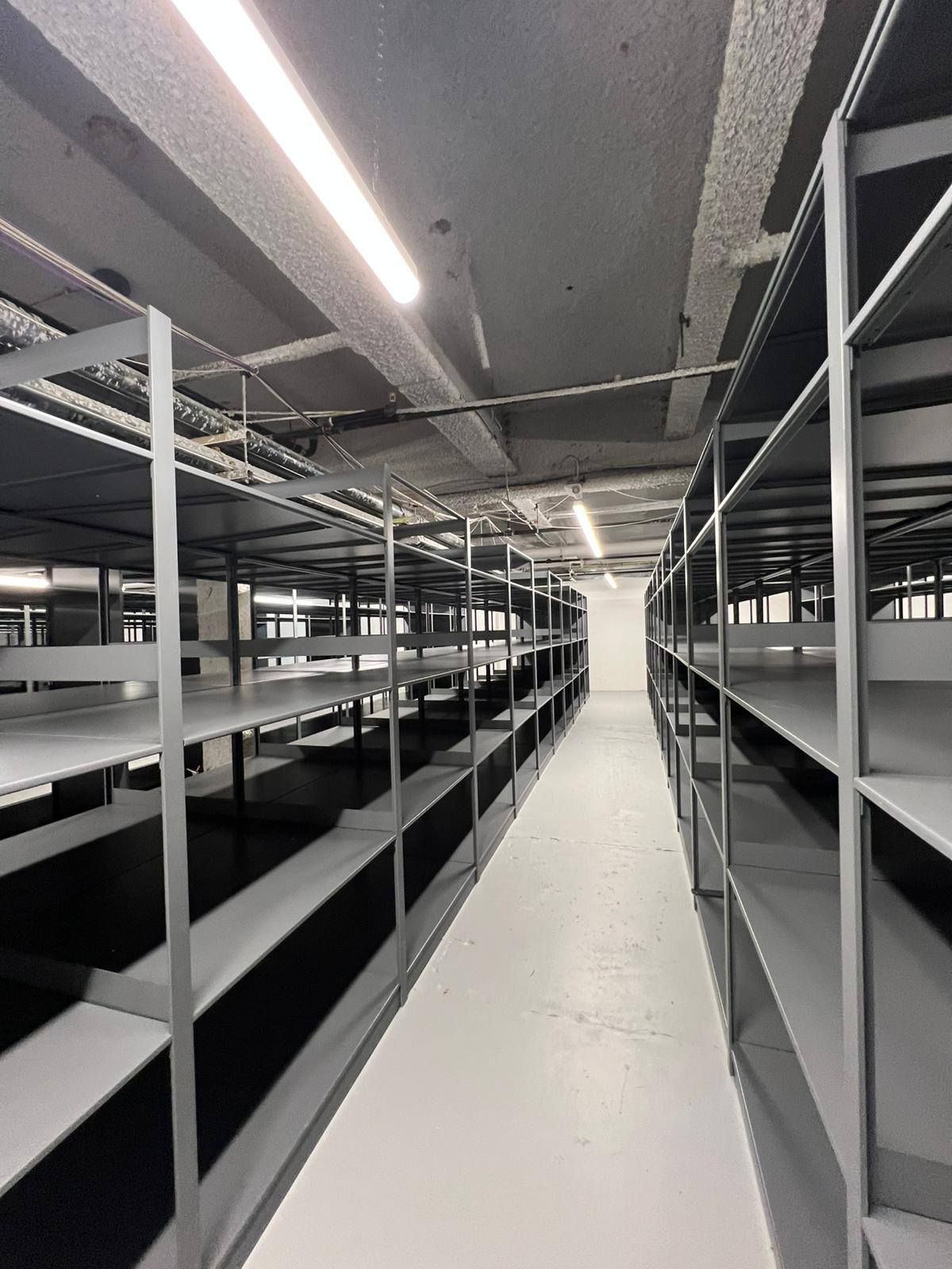 Empty industrial storage aisle with metal shelving and bright overhead lights