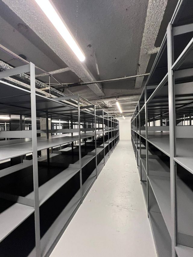 Empty industrial storage aisle with metal shelving and bright overhead lights