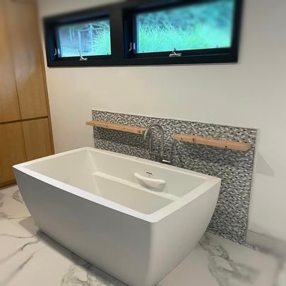 A bathroom with a bathtub and two windows