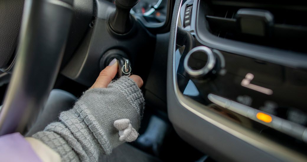 Up close to hand turning ignition in vehicle with car keys | Crowne Automotive