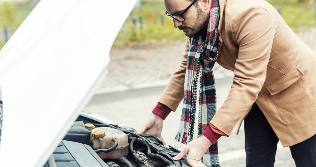 Man looking under hood of vehicle at engine | Crowne Automotive
