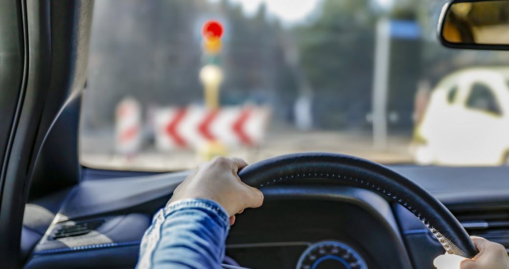 Driver's view from vehicle of man using steering wheel and seeing construction work ahead | Crowne Automotive