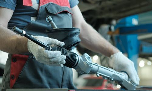Technician holding tool inside garage | Crowne Automotive