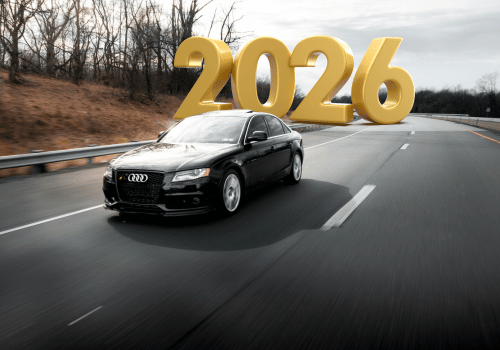Black car driving down road with yellow text of 2026 behind car | Crowne Automotive