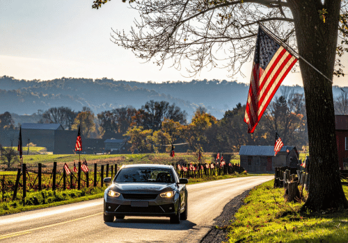 Vehicle driving down road with American flags on the sides of the road | Crowne Automotive