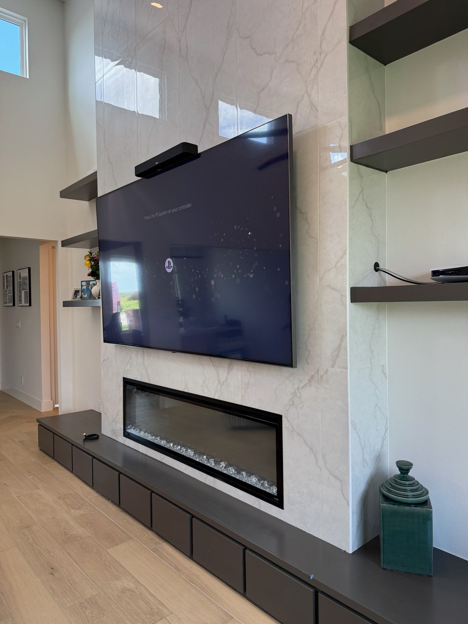Modern living room wall with a mounted TV, linear fireplace, built-in shelves, and dark cabinets