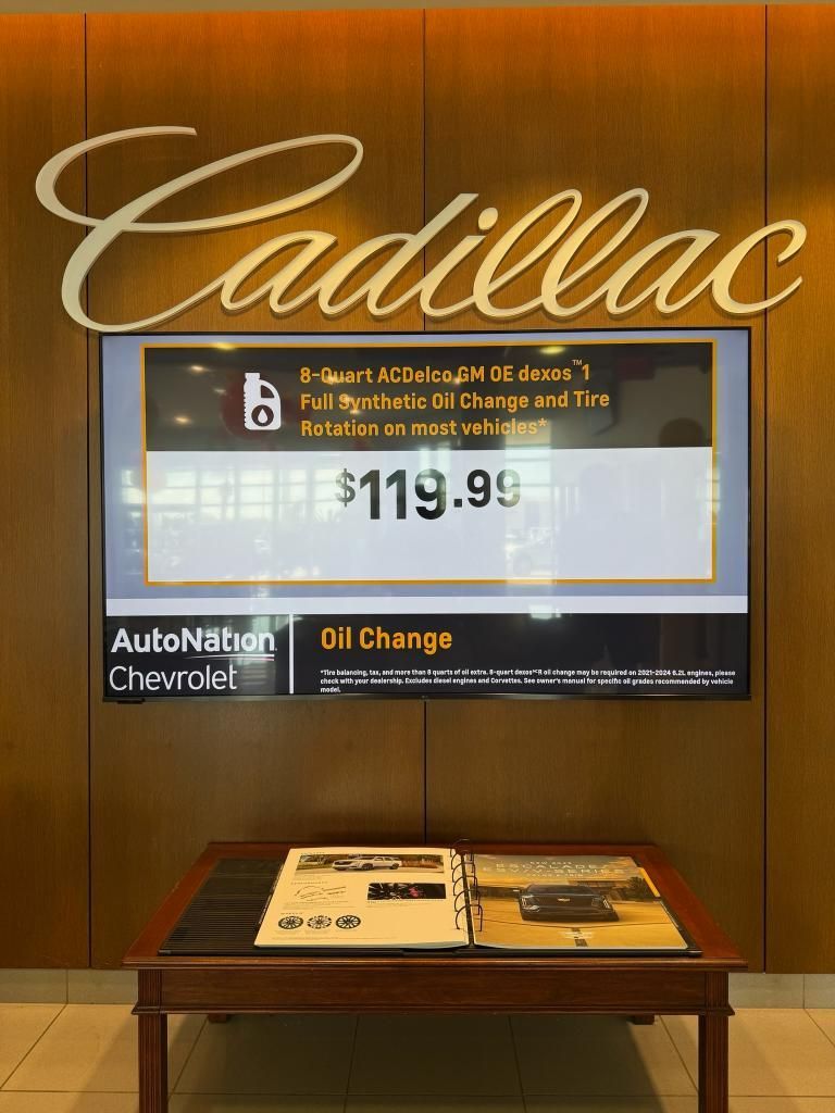 Cadillac dealership with sign offering oil change for $119.99. AutoNation Chevrolet logo.
