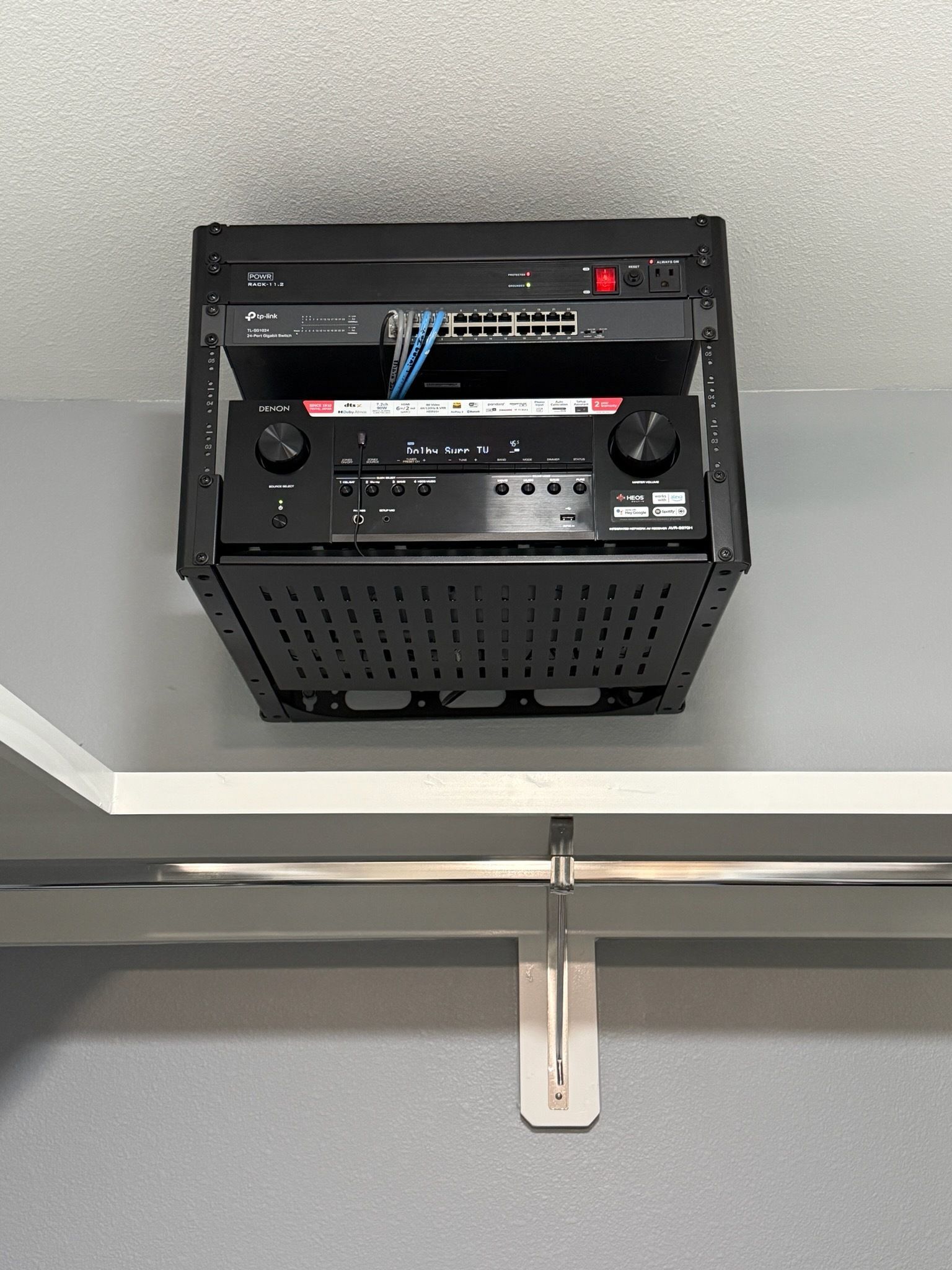 Black audio/visual equipment rack mounted above a shelf, containing various electronics.