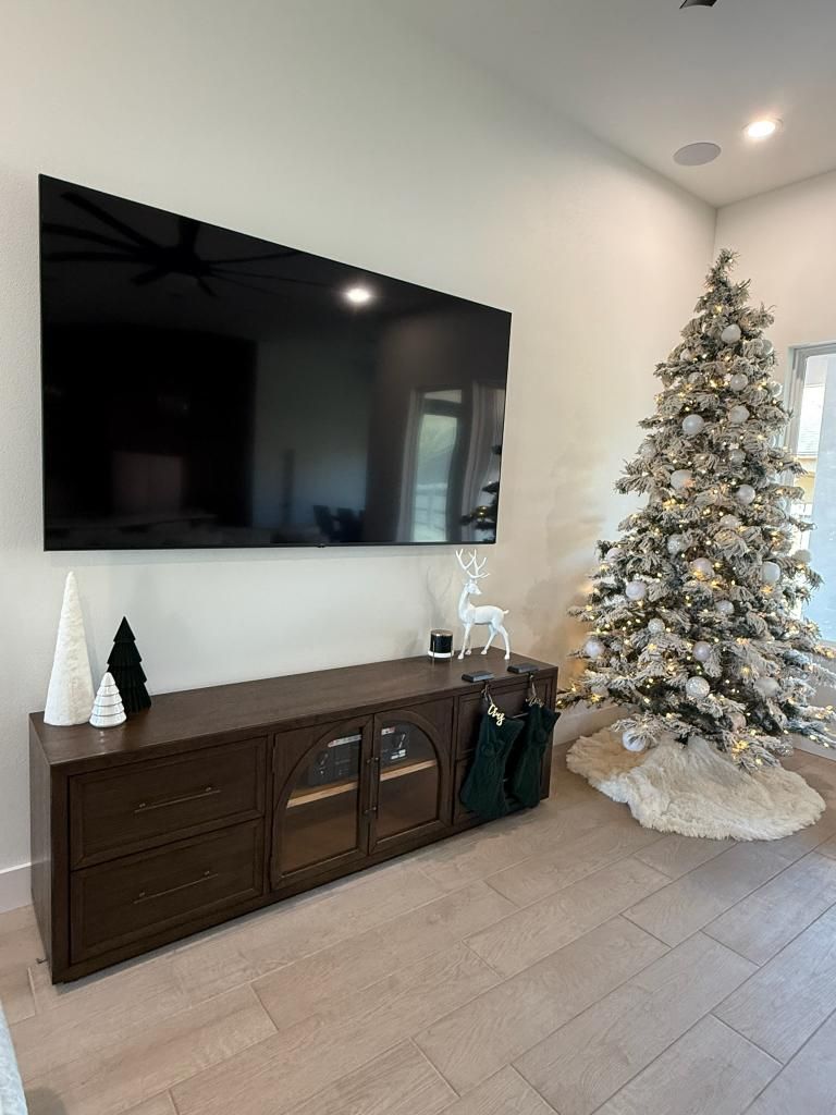 A dark brown entertainment center and a Christmas tree in a room with light-colored walls and flooring.