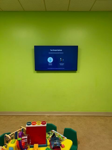 A children 's room with a table and chairs and a flat screen tv on the wall