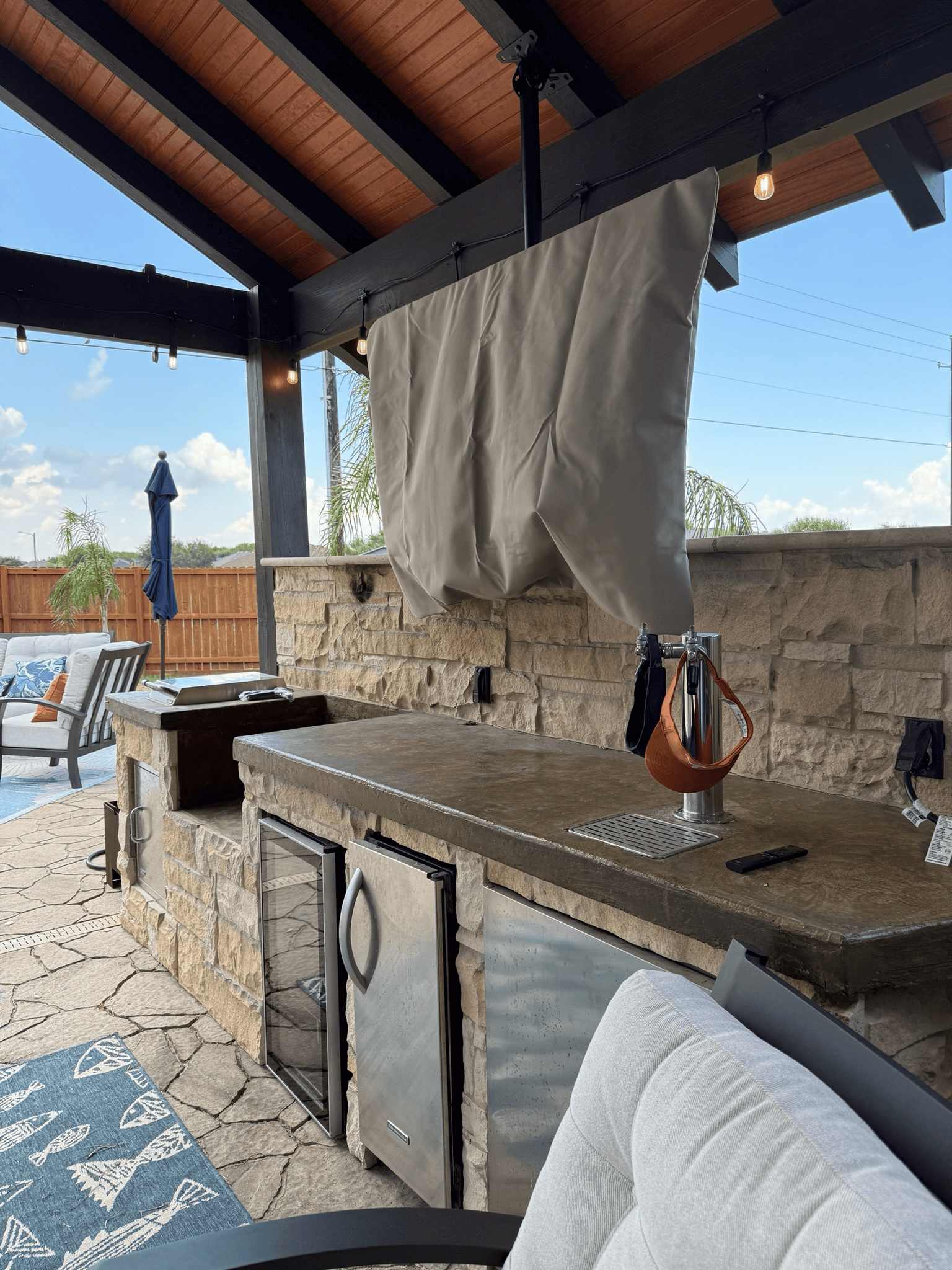 Outdoor kitchen with stone counters, stainless steel appliances, and covered TV.