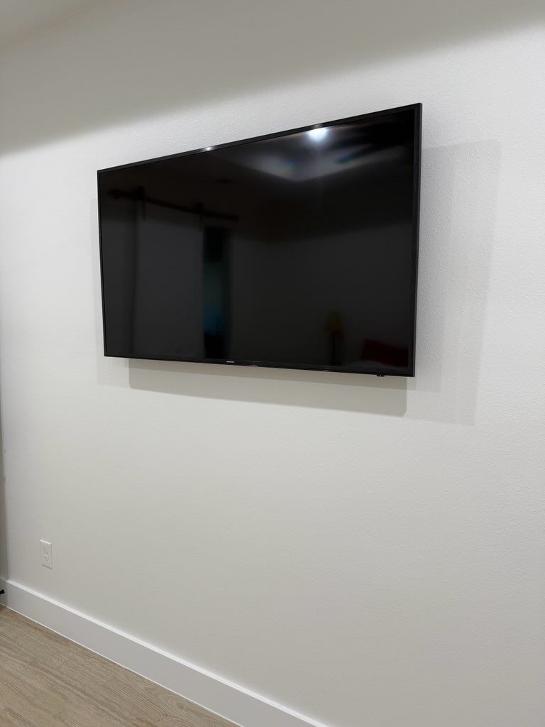 A flat screen tv is mounted on a white wall.